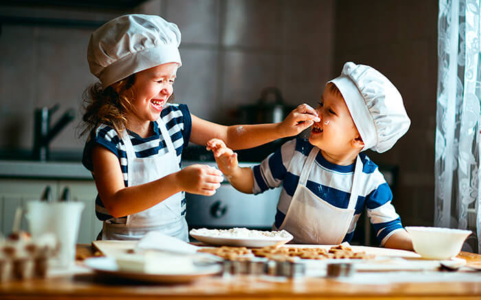 niños con gorro de cocinero haciendo galletas