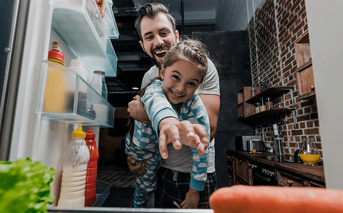 Adulto con niña jugando con el frigorífico abierto