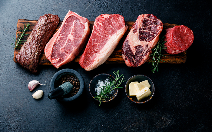 piezas de carne sobre una encimera para atemperar junto a recipientes con especias