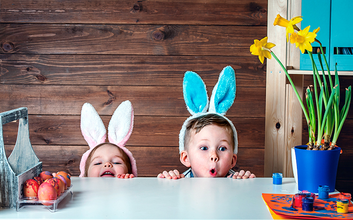 niños disfrazados de conejo pintando huevos de pascua en la cocina