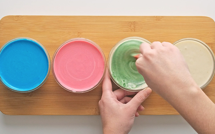 manos de niño haciendo pintura de colores con leche en tarros de cristal
