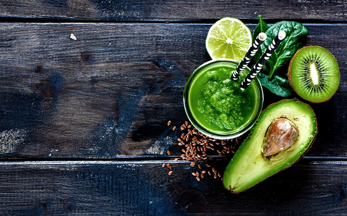 batido saludables de aguacate y kiwi con limón y avena en un vaso con pajitas negras