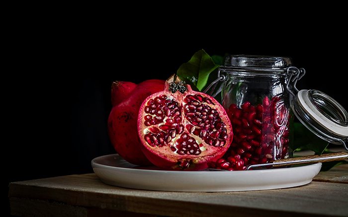 granada abierta por la mitad con la pepitas de la fruta en un tarro de cristal