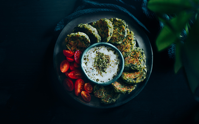 fritters de calabacin en plato con tomate