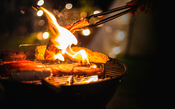 barbacoa con verdura y fuego y una mano cocinando