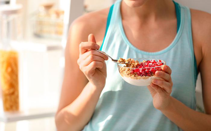 chica deportista comiendo bol de fruta y yogur