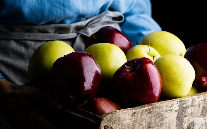 caja de manzanas sujeta por agricultura con delantal