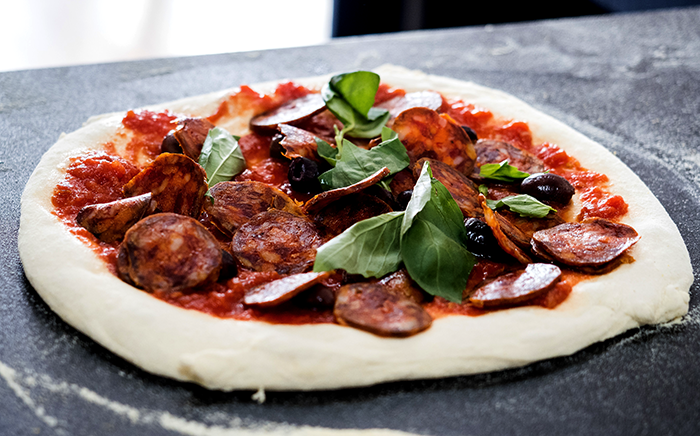 pizza sin hacer con chorizo y albahaca