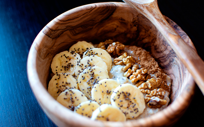 bol y cuchara de madera con plátano, nueces, miel y yogur