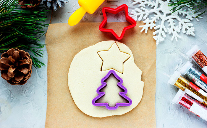 pasta de sal sobre un papel marrón y cortador de galletas con formas navideñas encima