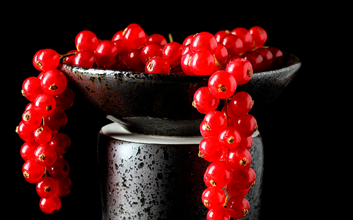 frutos rojos dentro de una jarra negra cayendo por los laterales