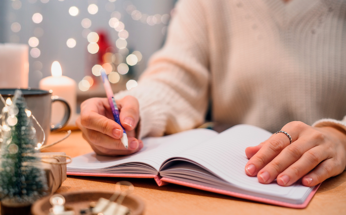 mujer escribiendo en un cuaderno con adornos de navidad