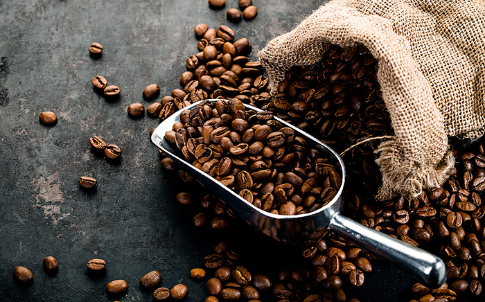 saco con granos de café sobre una mesa con un cazo metálico