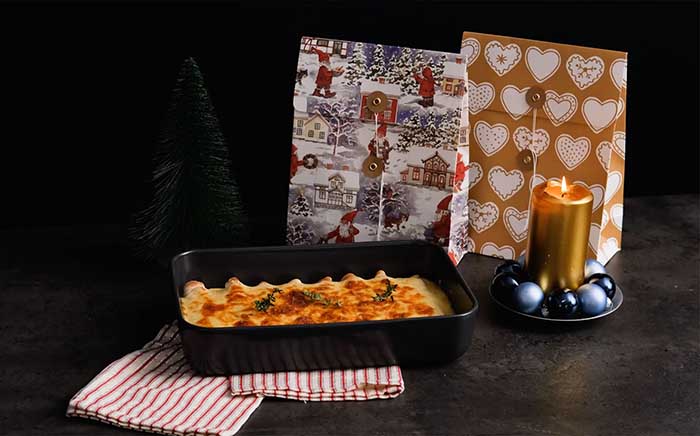 Fuente de canelones de foie y crepes para menú navideño con regalo de Navidad detrás