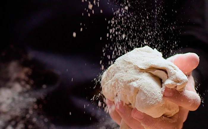 Masa casera con harina sujetada por una mano