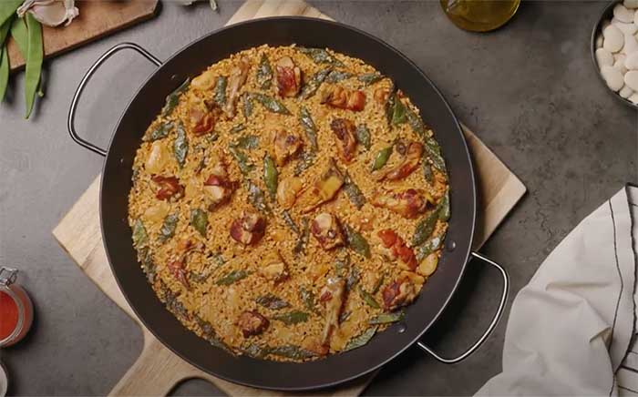 Paella valenciana auténtica sobre tabla de madera arroces más populares