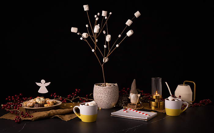 mesa de navidad con adornos manuales y un centro de mesa de ramas y nubes de algodón