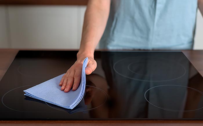 Mano limpiando la superficie de una placa con una bayeta azul