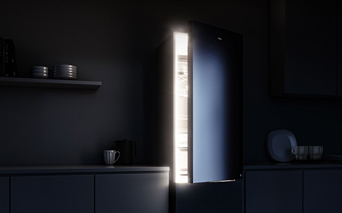 Frigorífico semi abierto con luz LED interior activada en una cocina a oscuras