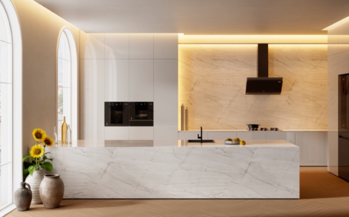 Cocina abierta en tonos blancos con campana de cocina de inducción, horno y microondas de la serie Van Gogh Museum Edition de Teka en color negro, con iluminación lateral natural desde la izquierda y un jarrón en el suelo con girasoles