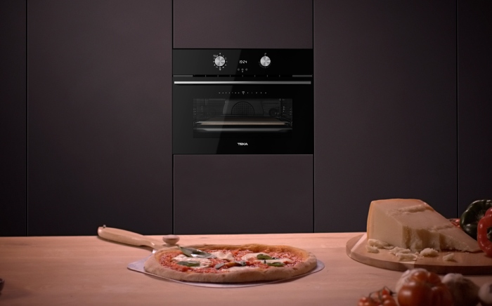 Horno con pirólisis MaestroPizza de Teka en acabado negro con una pizza casera recién hecha sobre una encimera de madera