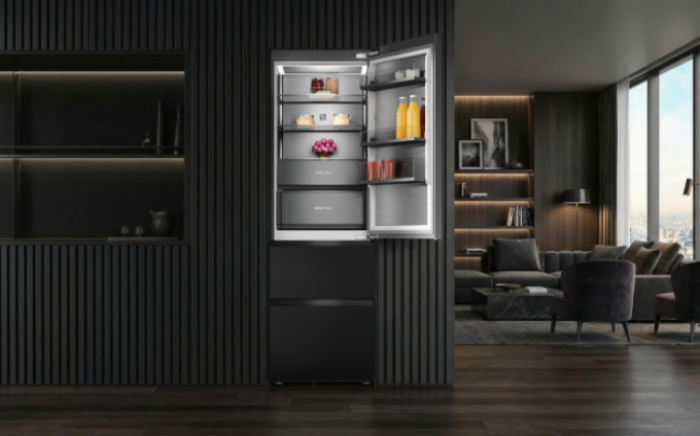 Frigorífico In-Line de Teka de la serie G1 abierto con alimentos y bebidas en el interior en una cocina de diseño integrada en el salón