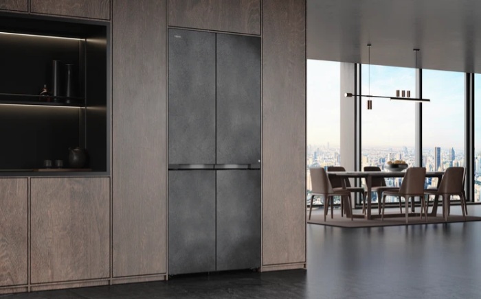 Frigorífico In-Line slot-in de Teka gama Maestro con cuatro puertas en una cocina con acabado de madera oscuro junto a un salón moderno