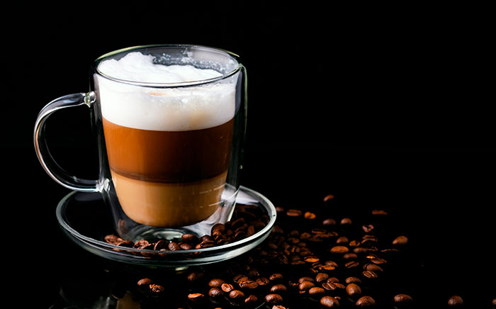 Café bombón with condensed milk and coffee beans around