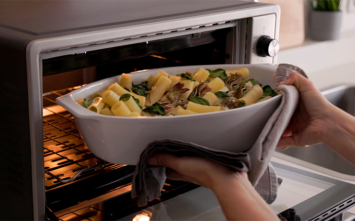 Small oven on a worktop with a plate of fresh made pasta compact kitchen appliances