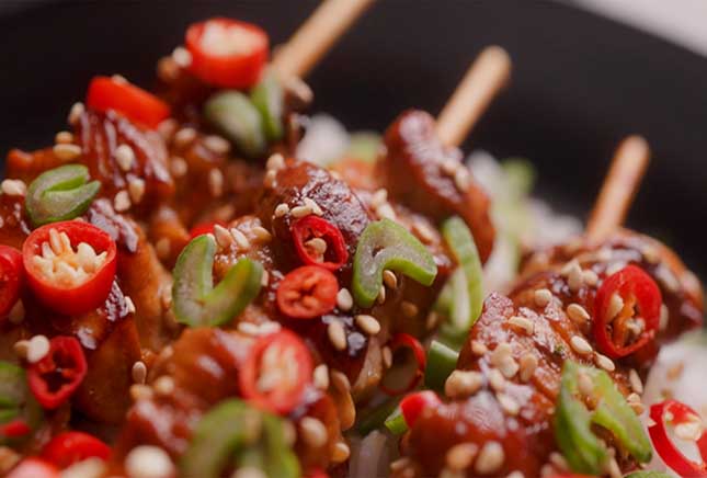 Teriyaki chicken skewers with chili and sesame seed cooked on a barbecue