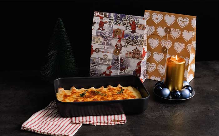 Platter with foie and crepes cannelloni on a dark surface over teatowels cooked on an oven with Christmas gifts behind