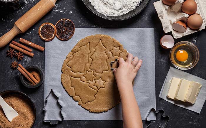 Children cutting biscuits on a dough over parchment paper