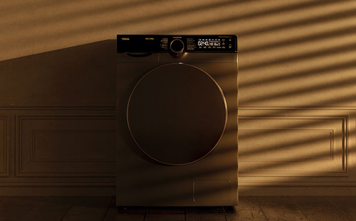 a dryer washing machine in the shadows of a laundry room 