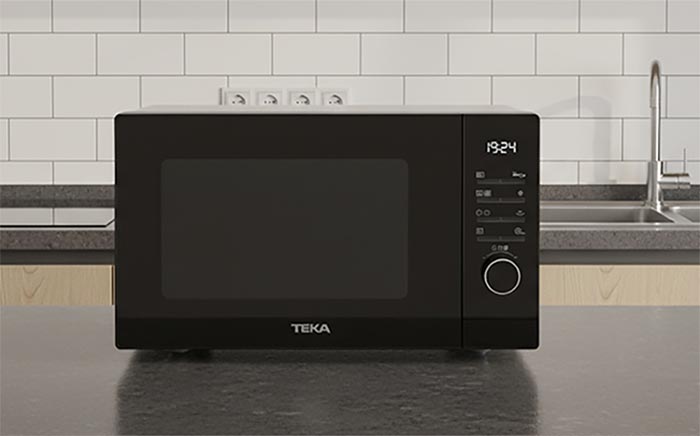 New black microwave by Teka on a countertop with a white kitchen background