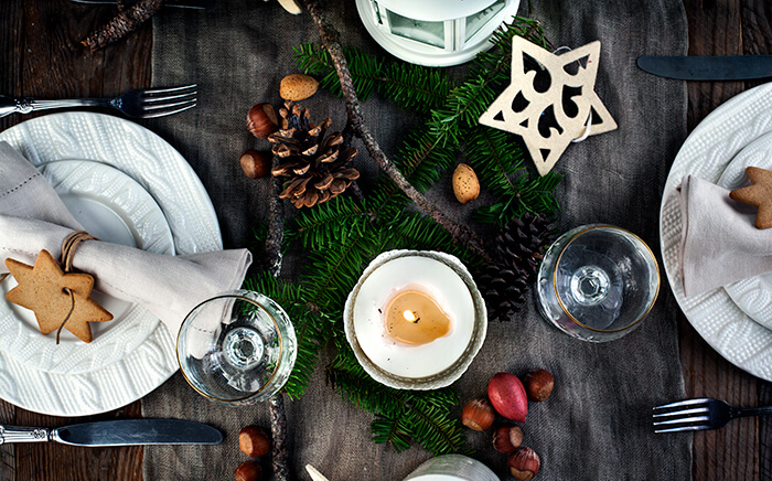 Table ready for a Christmas meal with candles, pineapples, plates and other Christmas-themed decoration