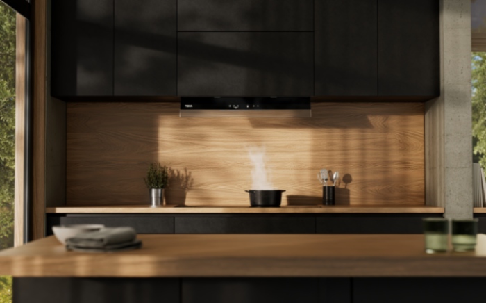 Kitchen appliances for everyday use in a dark, wood-toned kitchen, with a hot pot on the Teka hob and the Integra hood in operation