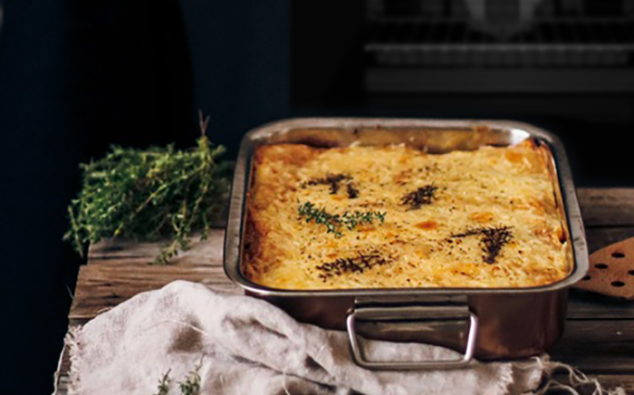 Meat cannelonni served in a metal traditional mould for oven over a wooden surface
