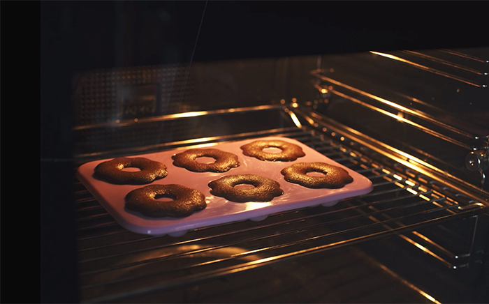 Baked buns in a silicone mould inside an oven