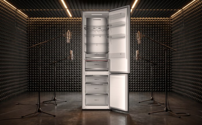 Open refrigerator positioned in a soundproof acoustic testing chamber surrounded by studio microphones to test low noise levels.