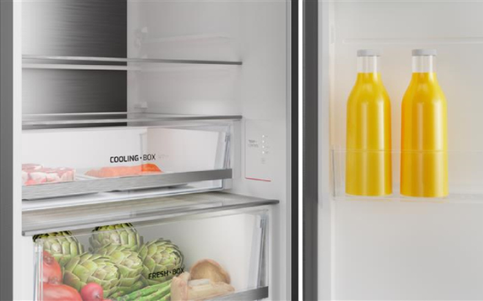 A detail view of a modern refrigerator interior with 'Cooling Box' and 'Fresh Box' drawers by Teka and bottles of juice.