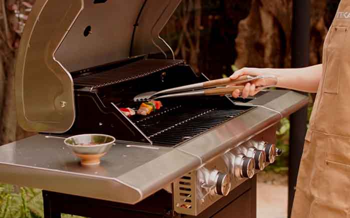 A chef flipping food in a Teka barbeque with lid