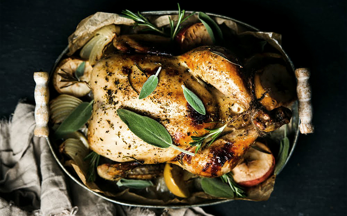 Chicken cooked in the microwave in a dish with laurel, lemon, rosemary and onions