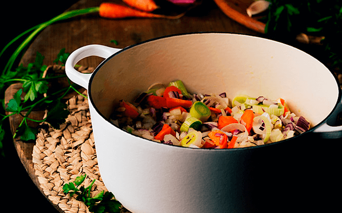 Homemade preparation of a stew where you can see the cut vegetables in a white traditional pot