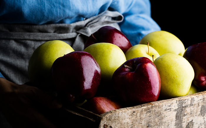 somebody is carrying a wooden drawer with fresh and bright red and yellow apples good for a healthy winter
