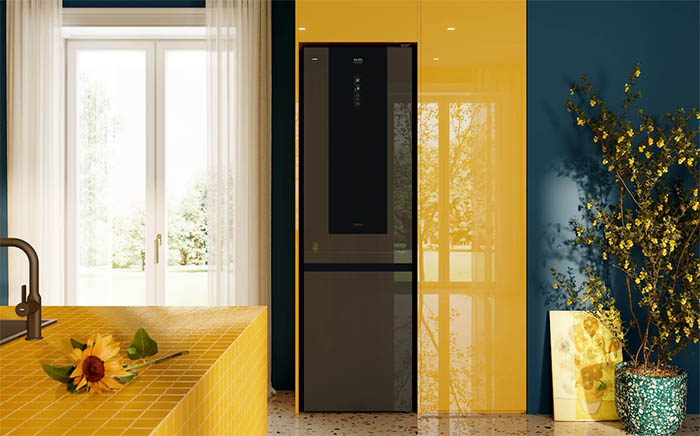 Yellow tone kitchen with natural light from a background balcony and a Van Gogh Museum edition refrigerator by Teka